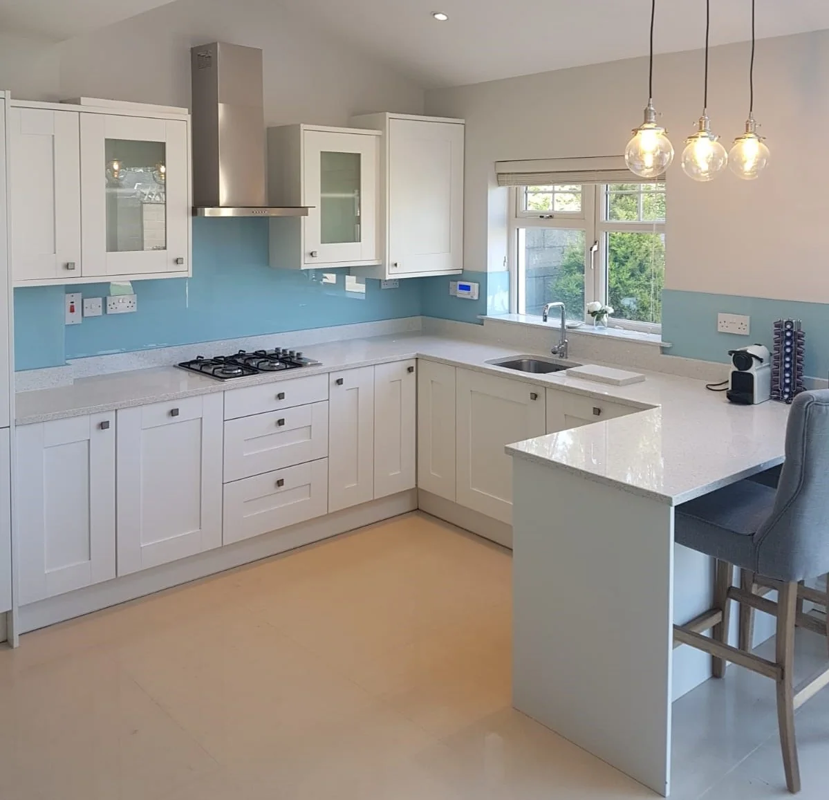 Light blue glass kitchen splashback with white cabinetry